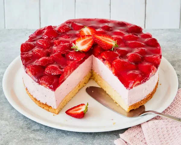 Eine köstliche Erdbeer Mascarpone Torte, üppig belegt mit frischen Erdbeeren und glänzendem Tortenguss. Ein Stück fehlt bereits.