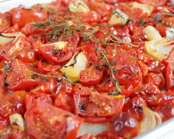 Tomatensauce aus dem Ofen: Geröstete Tomaten und Zwiebeln mit Rosmarin, die köstlich duften und bereit sind, zu einer aromatischen Sauce verarbeitet zu werden.