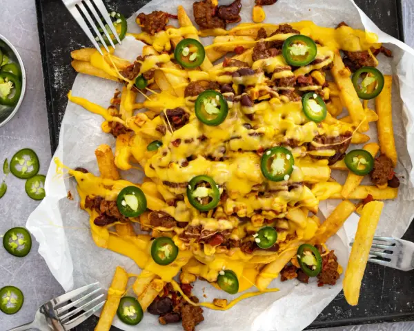 Pommes Frites mit Hackfleisch, Bohnen, Mais und geschmolzenem Käse, garniert mit Jalapeños. Ein köstliches Gericht mit **Chilli Cheese Sauce**.