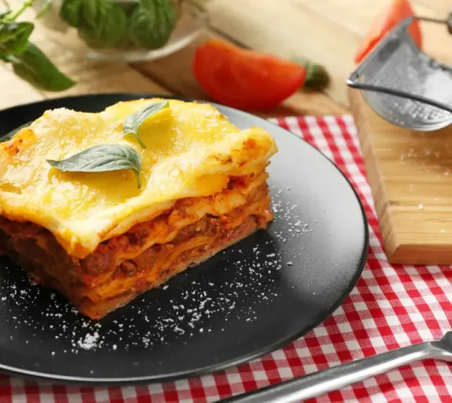 Ein Stück Lasagne mit Käse überbacken, garniert mit Basilikum. Perfekt für ein köstliches Lasagne Rezept.