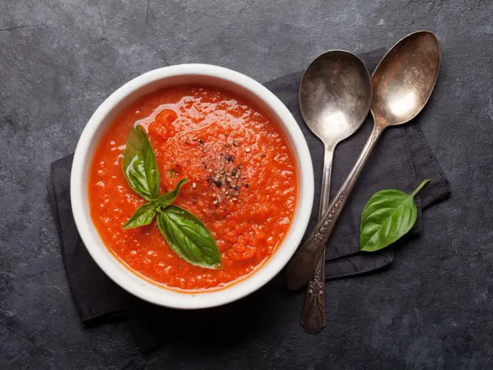 Schüssel mit frischer Tomatensuppe, garniert mit Basilikum. Perfekt, um Tomatensauce selber machen zu lernen.