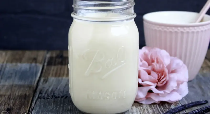 Selbstgemachter Kaffee-Sirup in einem Glas, mit Vanilleschoten und einer rosa Blume. Perfekt zum Kaffee creamer selber machen.