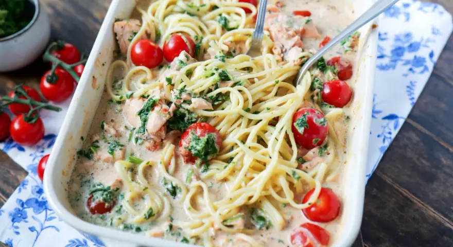 Cremige Lachs Spinat Pasta mit Kirschtomaten in einer Auflaufform, bereit zum Servieren.