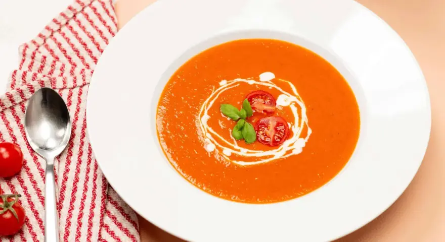 Ein Teller cremiger Tomatensuppe, garniert mit frischen Tomaten und Basilikum. Perfekt für ein einfaches Tomatensuppe Rezept mit frischen Tomaten.