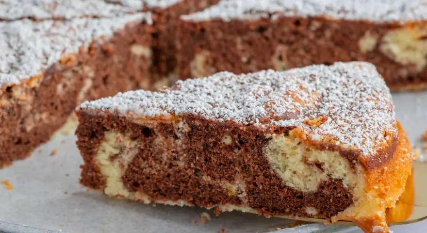 Ein Stück saftiger Marmorkuchen, bestäubt mit Puderzucker. Dieses fluffiger wolkenkuchen rezept ist ein Genuss!
