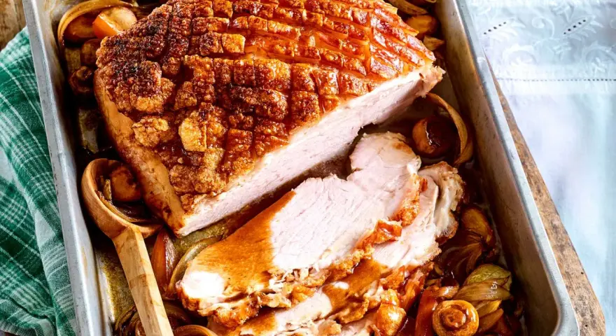 Saftiger Krustenbraten im Backofen, goldbraun und knusprig, mit Zwiebeln und Pilzen im Bratensaft. Ein Festmahl!
