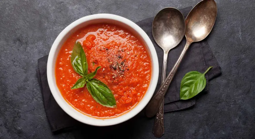Schüssel mit frischer Tomatensuppe, garniert mit Basilikum. Perfekt, um Tomatensauce selber machen zu lernen.