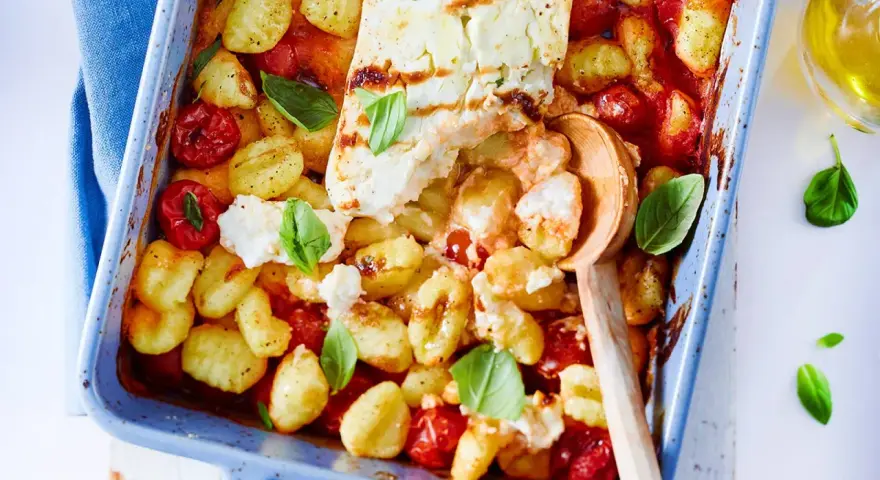 Gnocchi-Pfanne mit Feta, Kirschtomaten und Basilikum in einer blauen Auflaufform, bereit zum Servieren.