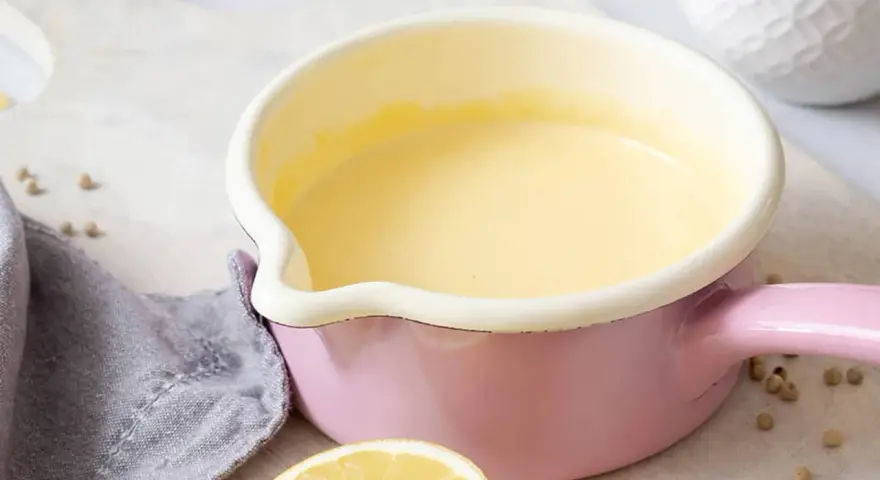 Frisch zubereitete Hollandaise in einem rosa Topf. So einfach ist es, Hollandaise selbst zu machen!