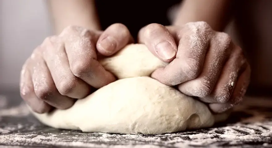 Hände kneten den pizzateig. Wie lange kneten? Bis er geschmeidig ist!