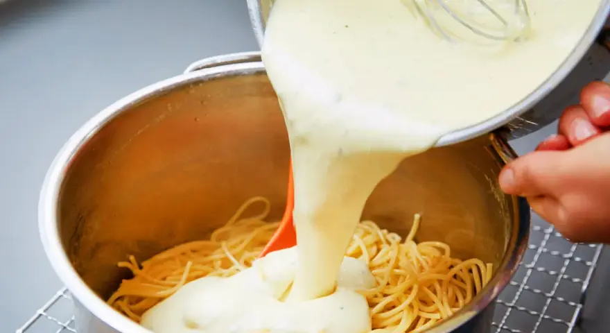 Cremige Käsesauce wird über Spaghetti gegossen. Ein einfaches Käsesauce Rezept für ein köstliches Gericht.