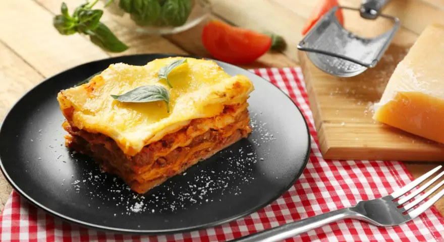 Ein Stück Lasagne mit Käse überbacken, garniert mit Basilikum. Perfekt für ein köstliches Lasagne Rezept.
