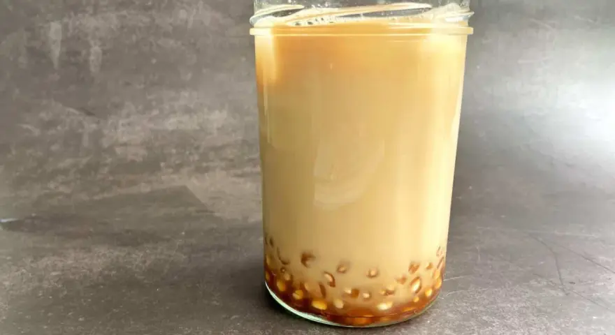 Ein Glas cremiger Milch-Tee mit Tapiokaperlen am Boden. Das ist, was Bubble Tea ausmacht!