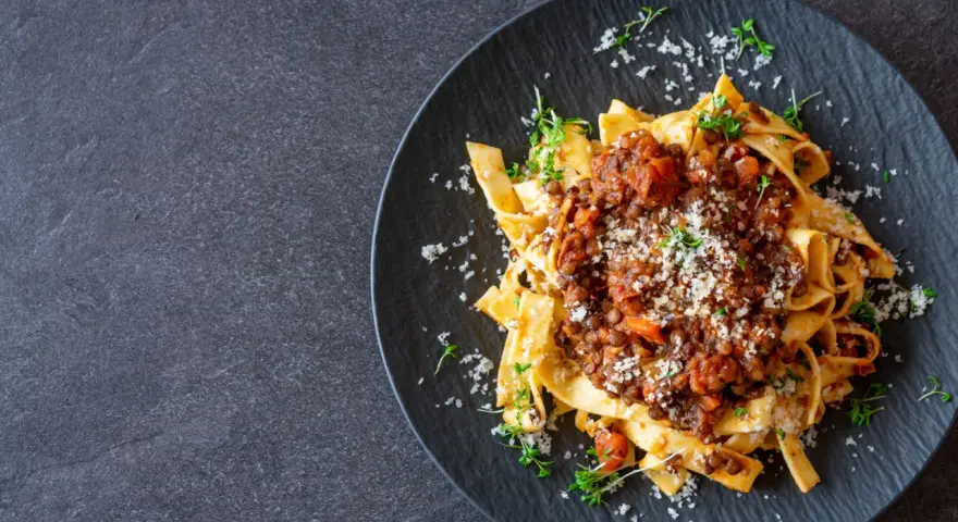 Jamie Oliver Bolognese auf Bandnudeln, garniert mit frischen Kräutern und Parmesan. Ein herzhaftes Gericht, das Lust auf mehr macht.