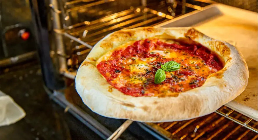Frisch gebackene neapolitanische Pizza mit Tomaten, Mozzarella und Basilikum im Ofen. Ein perfektes neapolitanische Pizza Rezept.