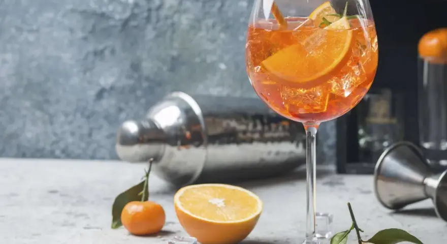 Erfrischender Aperol Spritz mit Orangenscheiben und Eiswürfeln, garniert mit Rosmarin. Ein Hauch von Sommer.