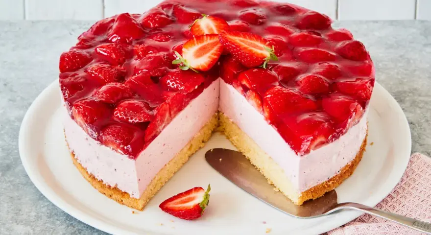 Eine köstliche Erdbeer Mascarpone Torte, üppig belegt mit frischen Erdbeeren und glänzendem Tortenguss. Ein Stück fehlt bereits.