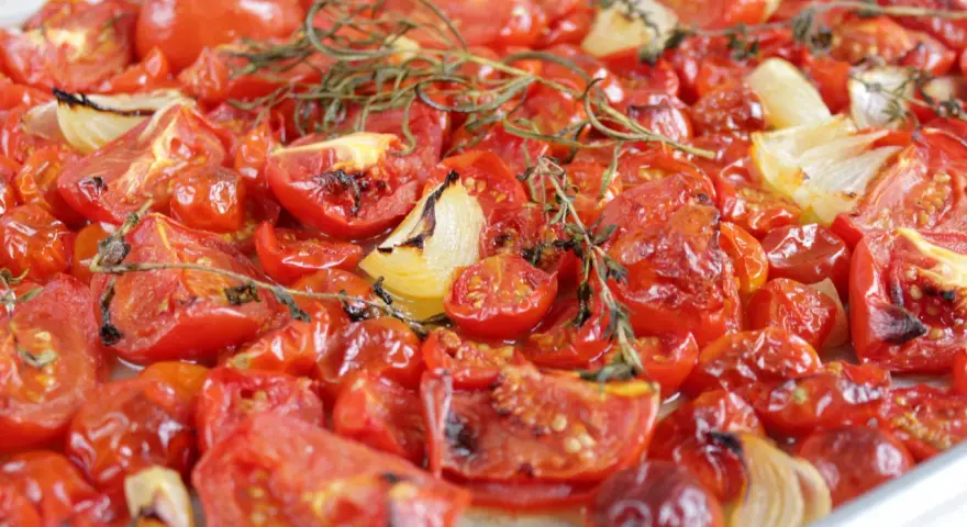 Tomatensauce aus dem Ofen: Geröstete Tomaten und Zwiebeln mit Rosmarin, die köstlich duften und bereit sind, zu einer aromatischen Sauce verarbeitet zu werden.