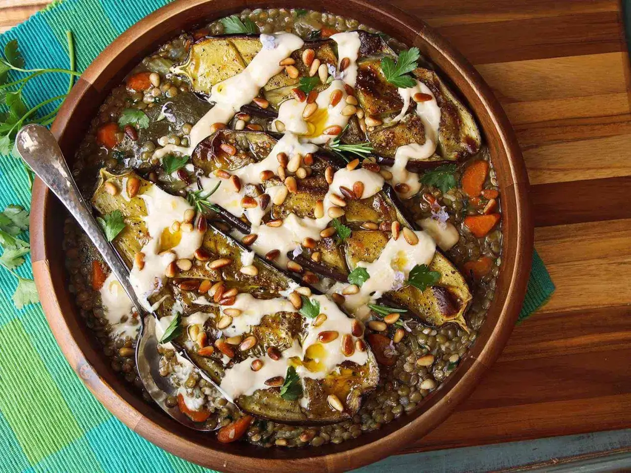 Baba ganoush mit Linsen, Auberginen, Karotten und Pinienkernen, beträufelt mit Tahini-Sauce.