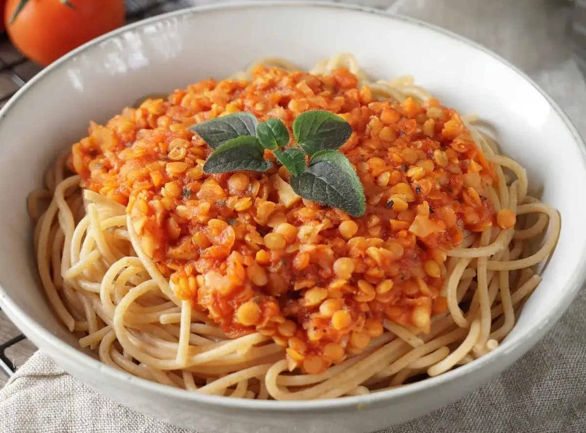 Herzhafte rote Linsen Bolognese auf Spaghetti, garniert mit frischen Kräutern. Ein köstliches, vegetarisches Gericht.