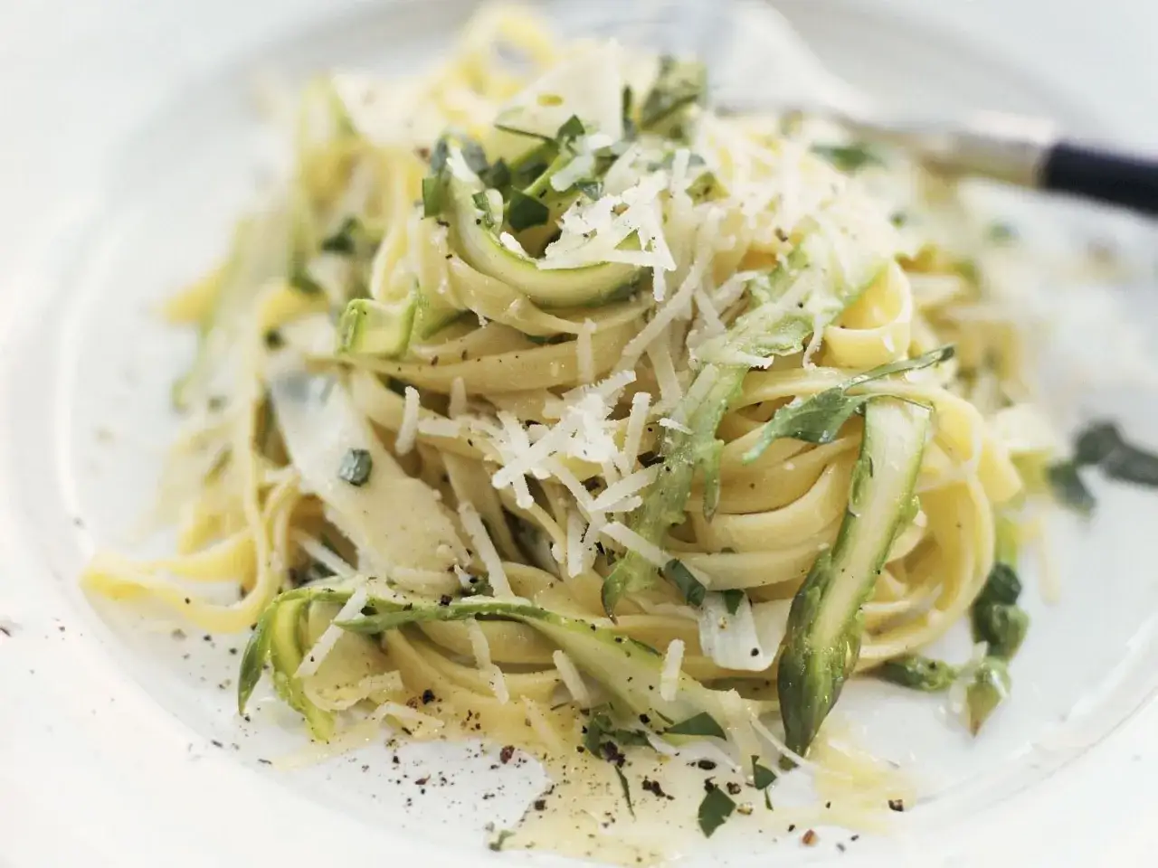 Spargel Pasta mit Parmesan und Kr&auml;utern, ein fr&uuml;hlingshaftes Gericht, das auf einem Teller serviert wird.