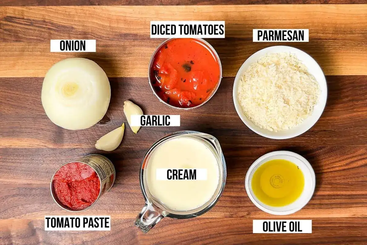 Zutaten f&uuml;r eine cremige Tomaten-Sahne-Sauce: Zwiebel, Knoblauch, gehackte Tomaten, Tomatenmark, Sahne, Parmesan und Oliven&ouml;l.
