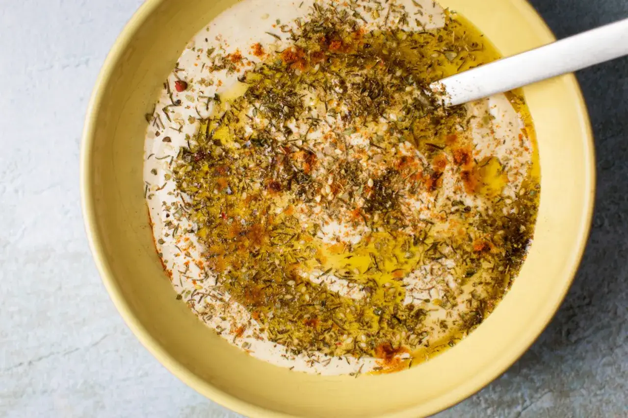 Cremiger Hummus, frisch zubereitet, mit Olivenöl, Kräutern und Paprikapulver garniert. Perfekt zum Hummus selber machen!