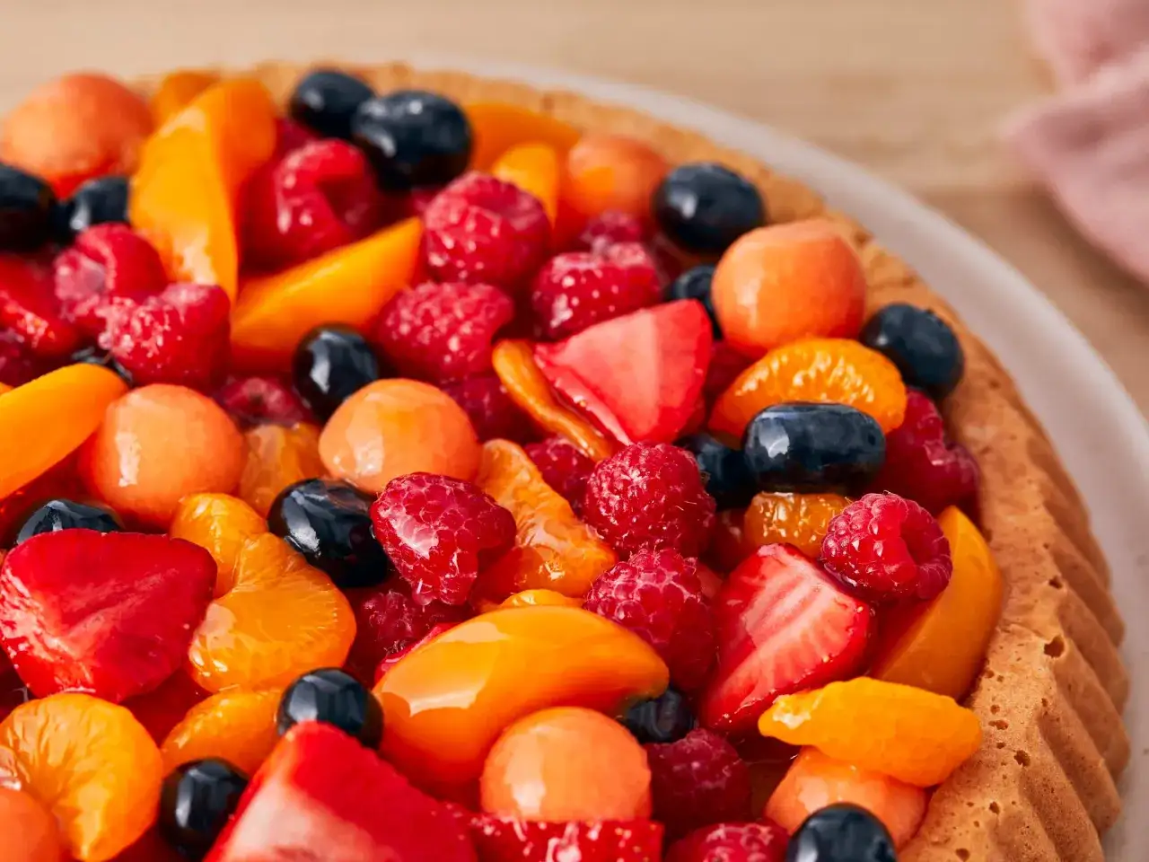 Fruchtiger Kuchen mit Erdbeeren, Himbeeren, Blaubeeren und Aprikosen. Perfekt, um Tortenguss selber machen zu üben und die Früchte glänzen zu lassen.