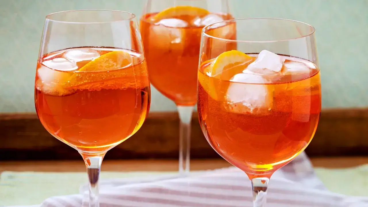Drei Gläser mit erfrischendem, alkoholfreiem Aperol, garniert mit Orangenscheiben und Eiswürfeln.