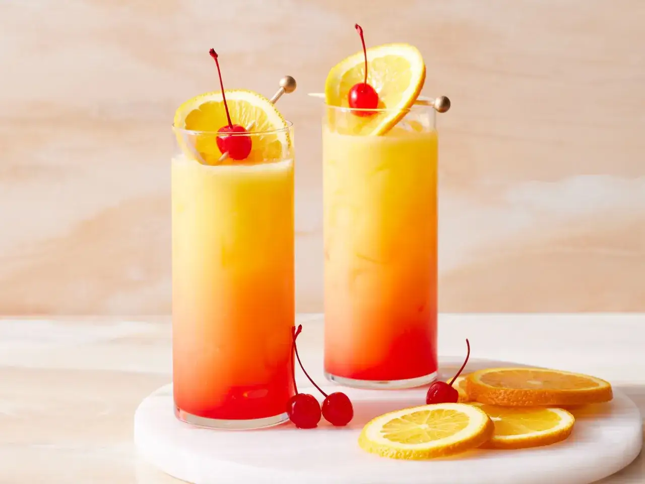 Zwei erfrischende Tequila Sunrise Cocktails mit Orangenscheiben und Kirschen, bereit f&uuml;r den Sonnenuntergang.