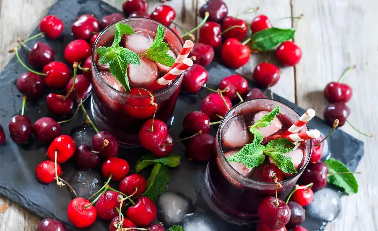 Erfrischender Kirschsaft selber machen: Zwei Gl&auml;ser mit Eis, Minze und Kirschen. Perfekt f&uuml;r hei&szlig;e Tage!