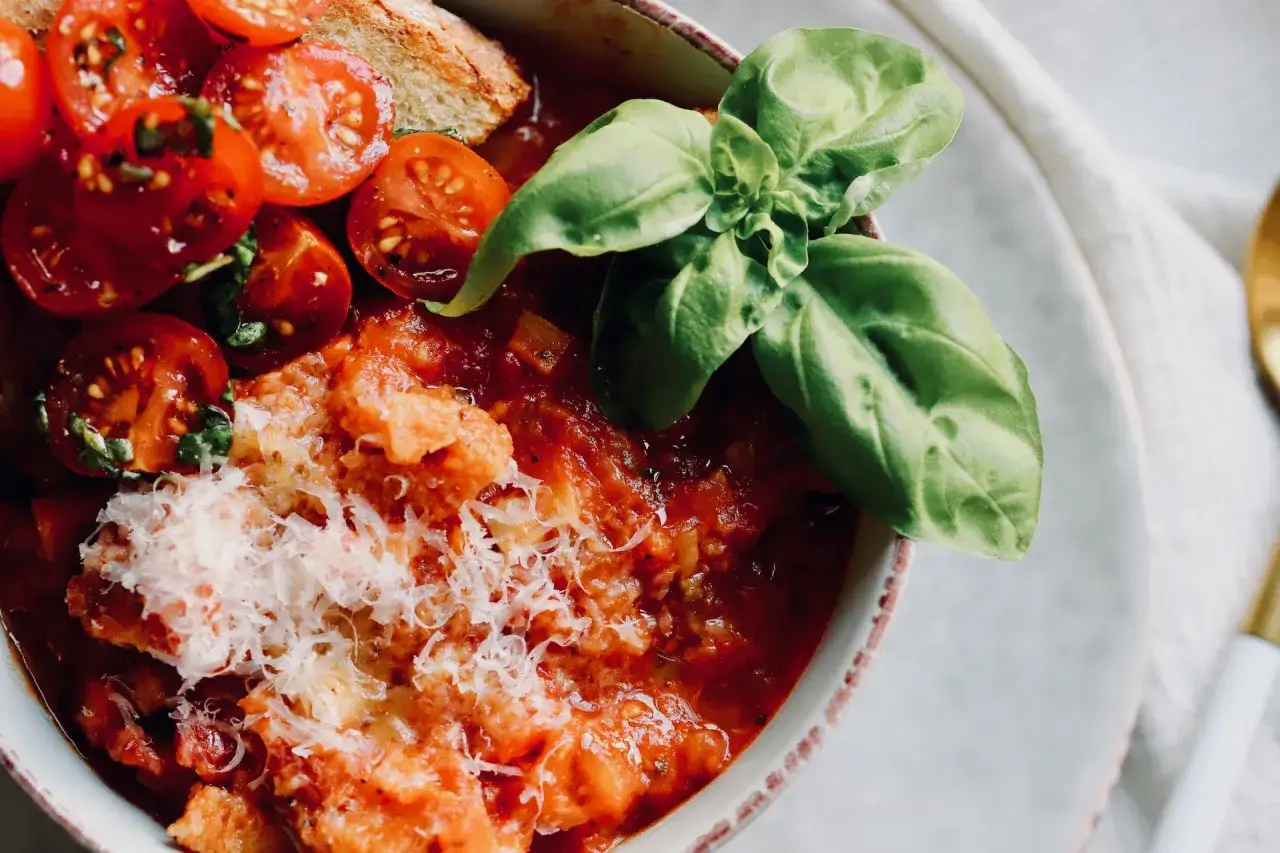 Schüssel mit köstlicher Tomatensuppe, garniert mit frischen Tomaten, Basilikum und Parmesan. Ein perfektes Rezept für Tomatensuppe mit frischen Tomaten.