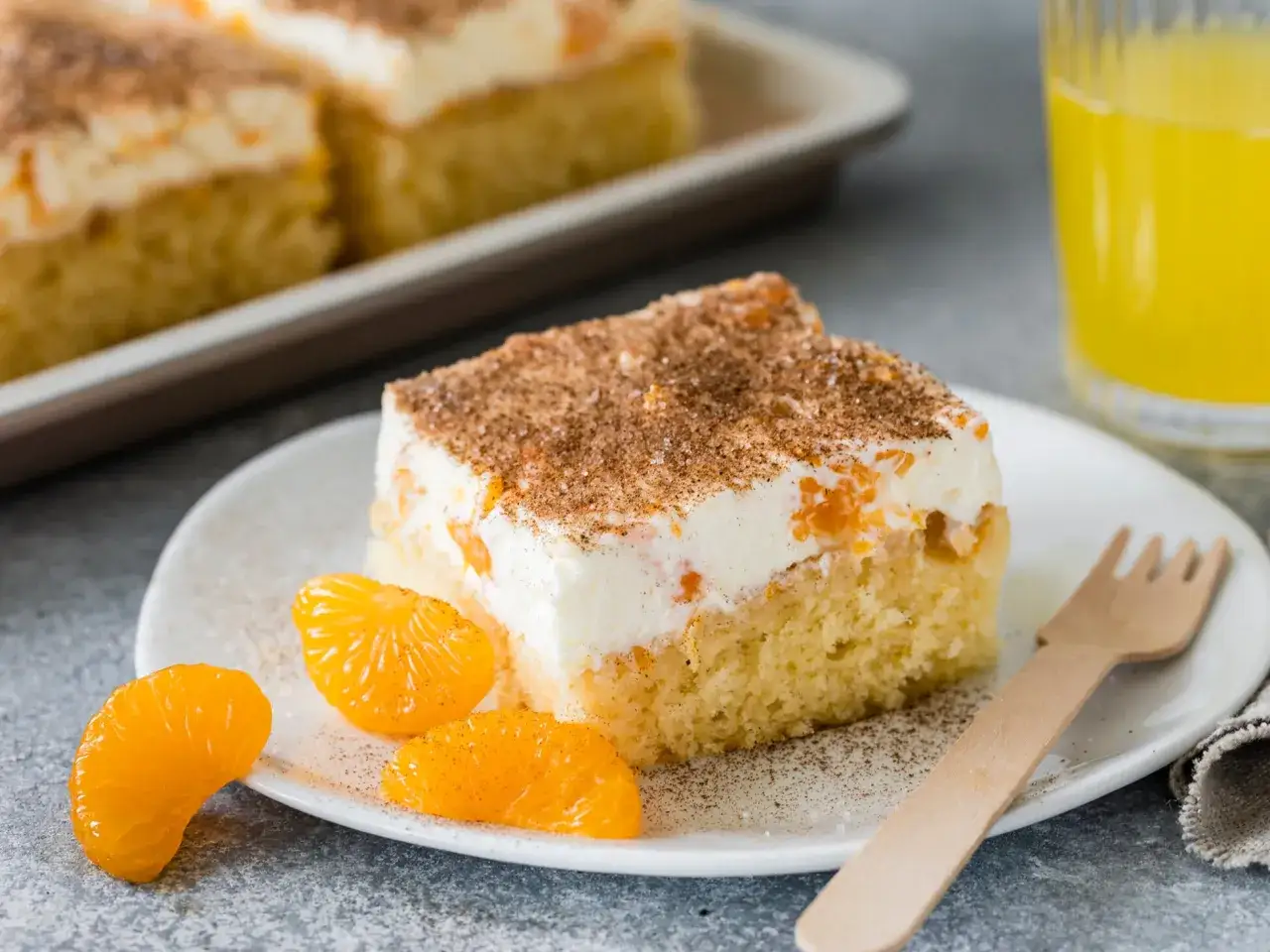 Ein St&uuml;ck saftiger Fantakuchen mit Mandarinen und Sahne, bestreut mit Zimt. Perfekt f&uuml;r ein Fantakuchen Rezept.