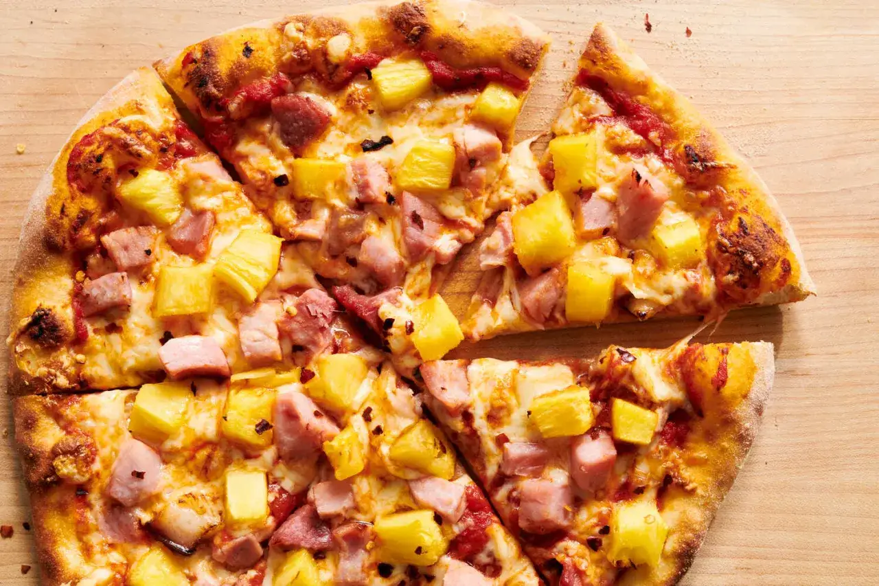 Eine k&ouml;stliche Pizza Hawaii mit saftigem Schinken und s&uuml;&szlig;en Ananasst&uuml;cken, goldbraun gebacken auf einem Holzbrett.