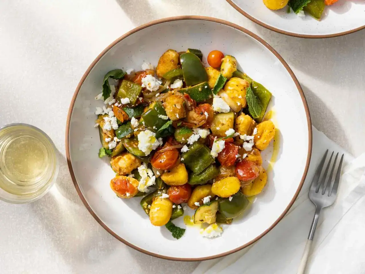 Gnocchi-Pfanne mit Feta, Paprika, Zucchini und Kirschtomaten, garniert mit frischer Minze.