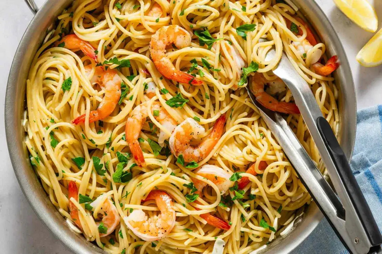 Spaghetti mit Garnelen, frisch zubereitet und mit Petersilie garniert, warten in einer Pfanne darauf, serviert zu werden.