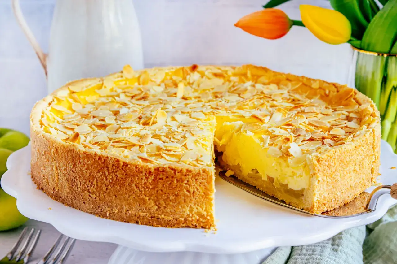Ein k&ouml;stlicher, schneller Apfelkuchen mit Schmand und Pudding, bestreut mit Mandelbl&auml;ttchen. Ein St&uuml;ck wurde bereits entnommen.