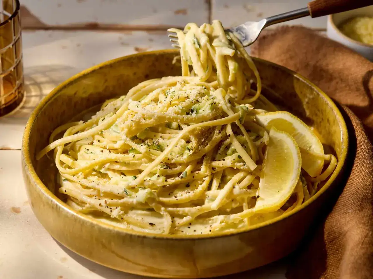 Zucchini-Zitronen-Pasta mit Parmesan und frischen Zitronenspalten, serviert in einer rustikalen Schüssel.