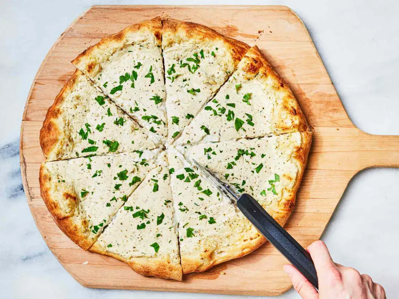 Eine k&ouml;stliche Pizza Bianca, in St&uuml;cke geschnitten und mit frischer Petersilie bestreut, wartet darauf, serviert zu werden.
