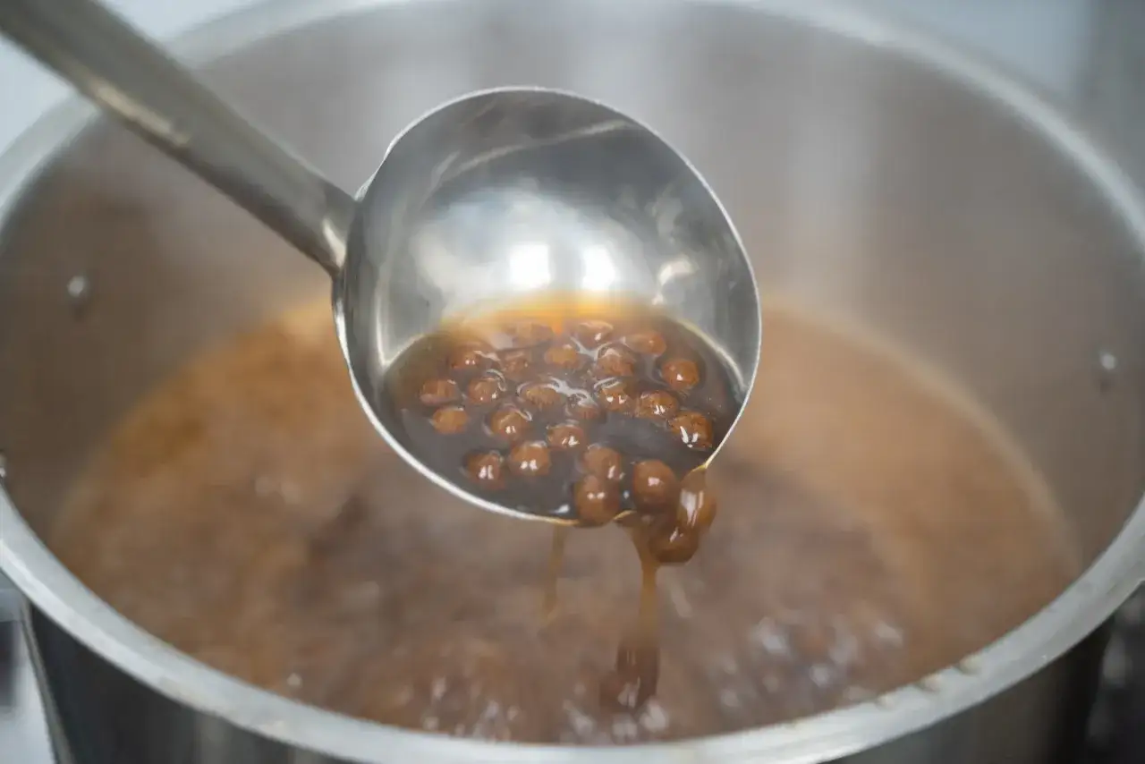 Sch&ouml;pfkelle hebt kochende Tapiokaperlen aus einem Topf. So einfach ist es, Bubble Tea Perlen selber machen!