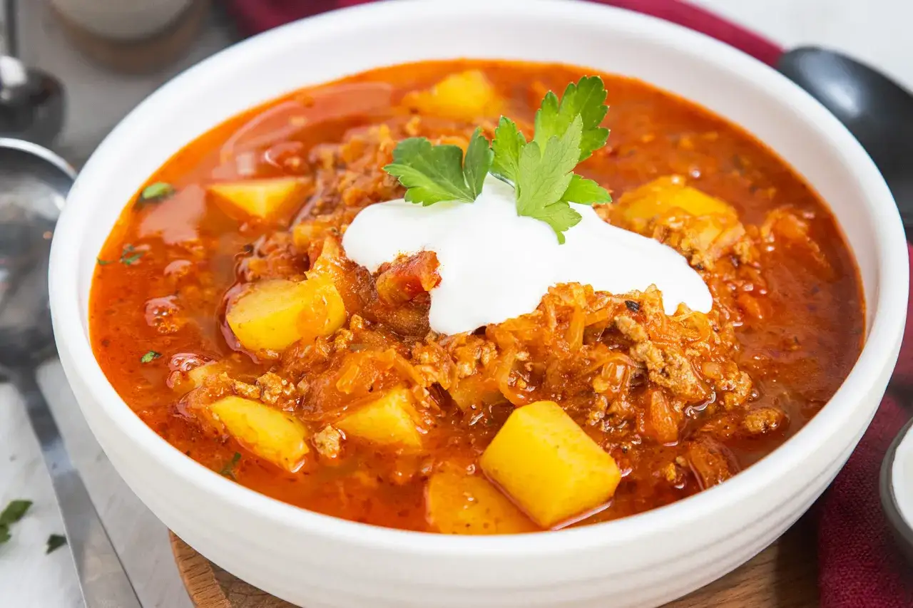 Herzhafte Mitternachtssuppe mit Hackfleisch und Sauerkraut, garniert mit einem Klecks Sauerrahm und Petersilie. Ein w&auml;rmendes Gericht f&uuml;r kalte N&auml;chte.