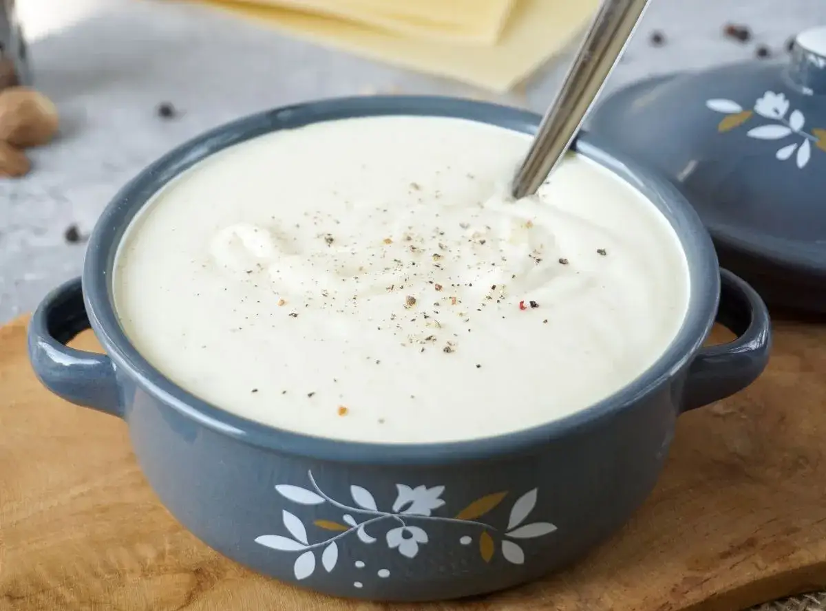 Cremige B&eacute;chamelsauce in einer grauen Sch&uuml;ssel, bestreut mit Pfeffer. Perfekt f&uuml;r Lasagne.
