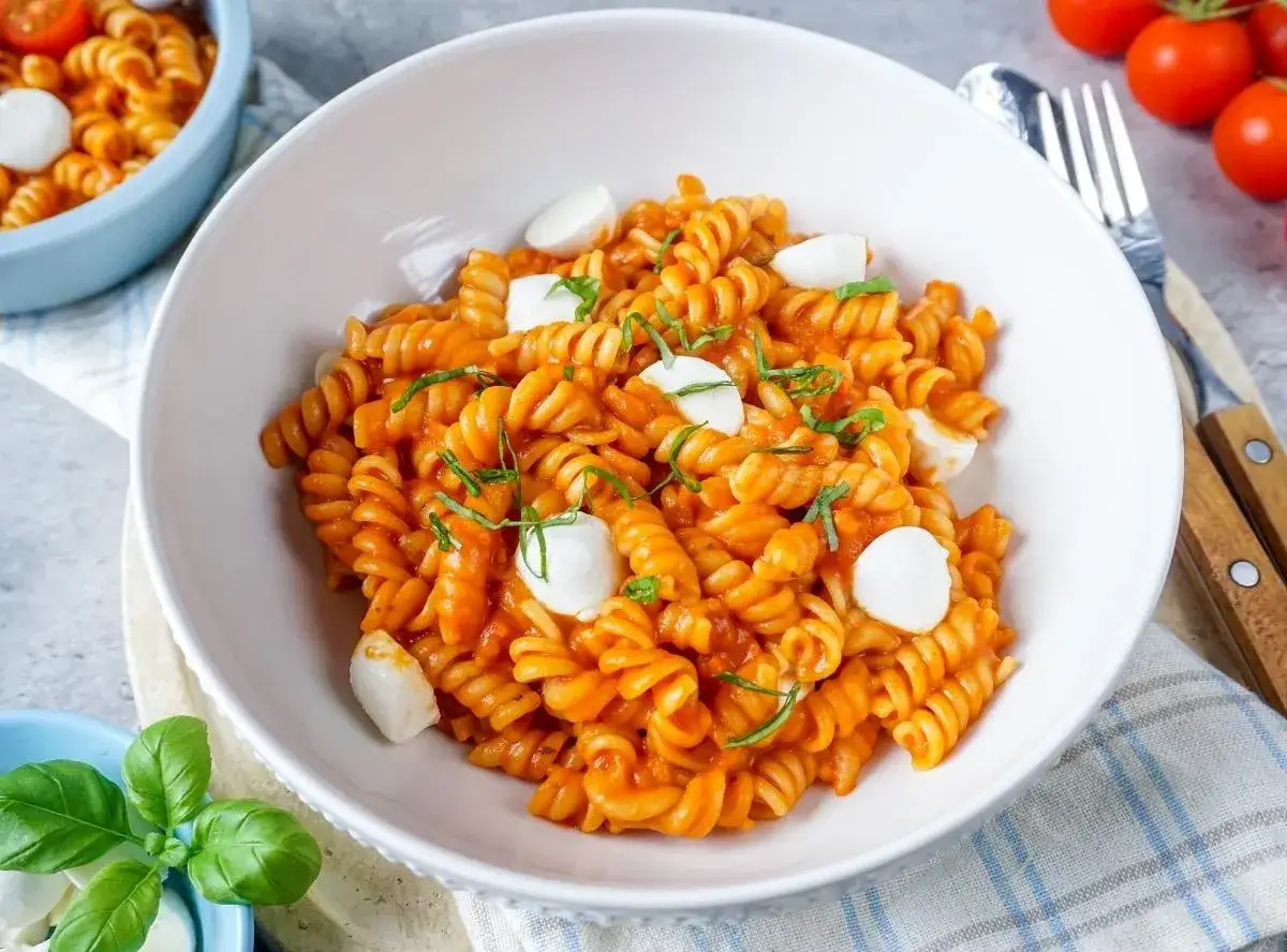 Eine Schüssel fusilli in Tomatensauce mit Mozzarella-Kugeln und Basilikum. Dieses Gericht ist ein einfaches und leckeres One-Pot-Pasta-Rezept.