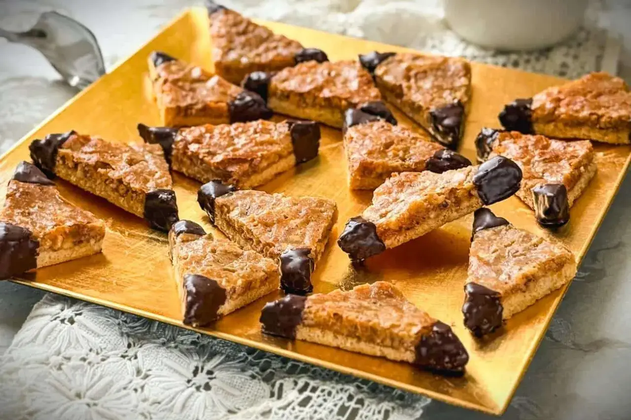 Dreiecke mit Nussecken-Rezept, knusprig gebacken und mit Schokolade verfeinert, liegen auf einem goldenen Teller.