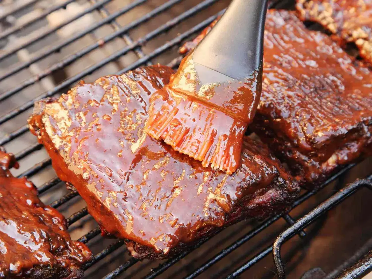 Rippchen werden mit einer k&ouml;stlichen bbq sauce auf dem Grill bestrichen.