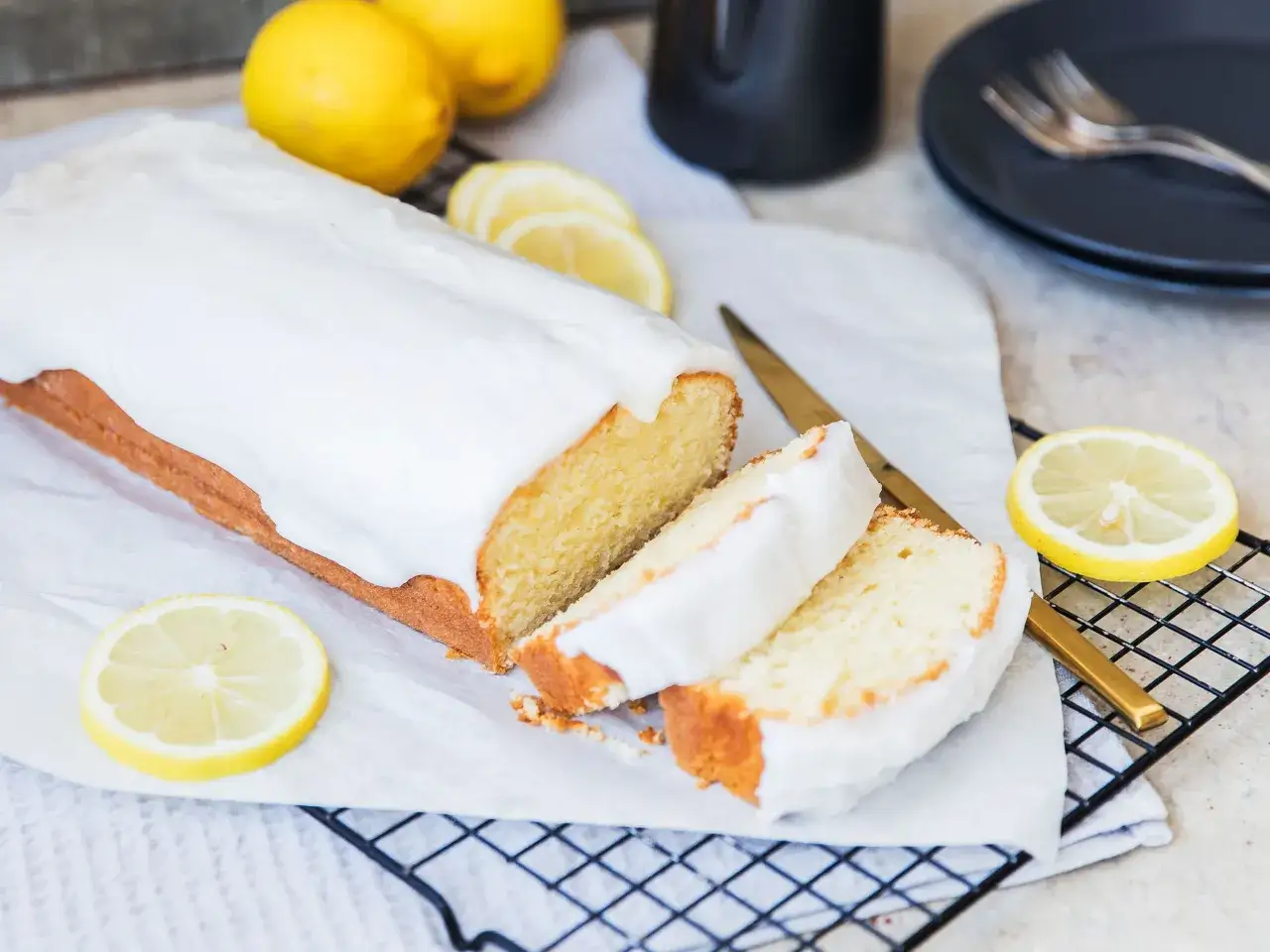Ein saftiger Zitronenkuchen mit Zuckerguss, perfekt f&uuml;r ein Lemon Drizzle Cake Rezept. Frische Zitronenscheiben zieren den Anschnitt.