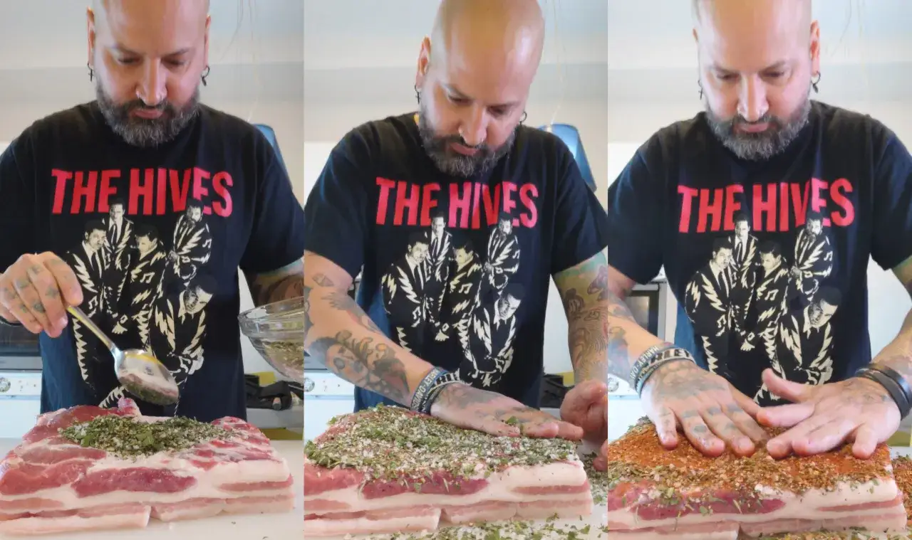 Mann mit Tattoos w&uuml;rzt Bauchspeck f&uuml;r den Backofen.