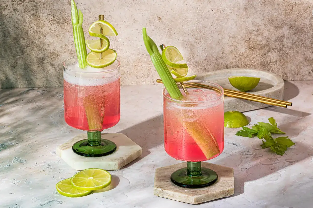Zwei erfrischende Sarti Spritz Cocktails mit Rhabarber und Limette, garniert mit Sellerie.