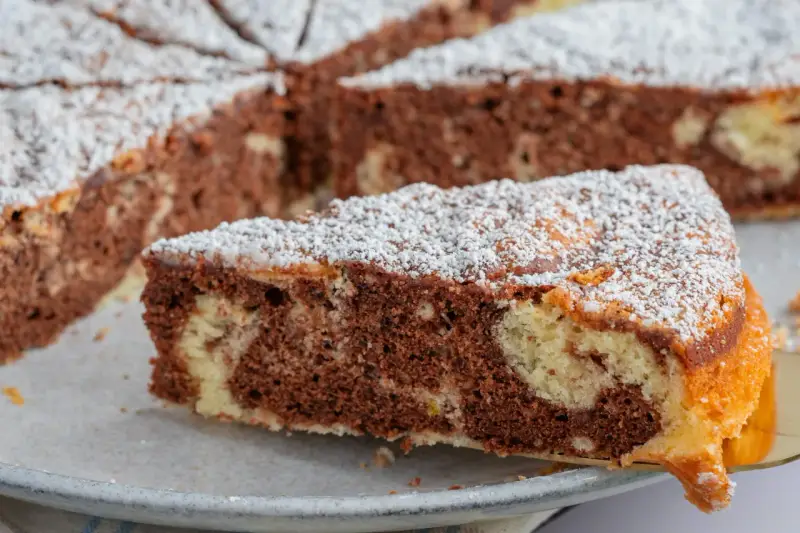 Ein Stück saftiger Marmorkuchen, bestäubt mit Puderzucker. Dieses fluffiger wolkenkuchen rezept ist ein Genuss!