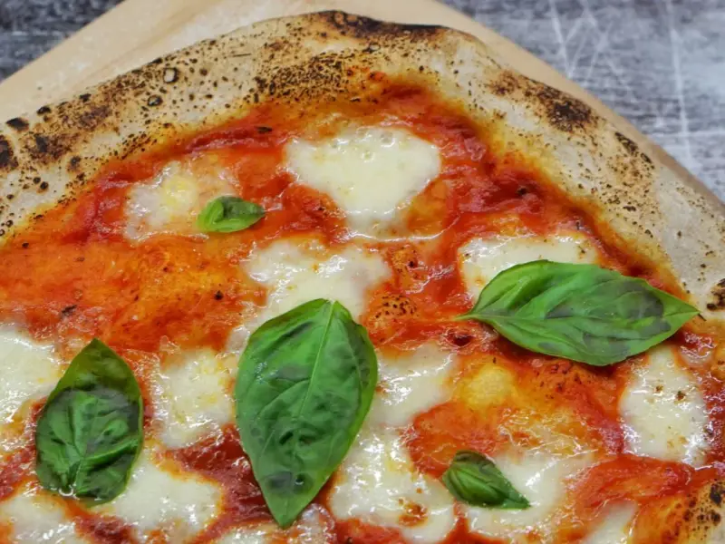 Eine köstliche Pizza Margherita mit geschmolzenem Mozzarella, leuchtend roter Tomatensauce und frischem Basilikum auf einem knusprigen Teig.